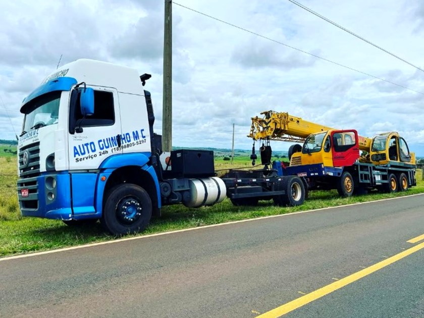 Guincho da MC Auto Guincho ao lado de um guindaste e de uma escavadeira em uma estrada rural
